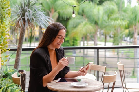 uma mulher sentada a uma mesa com uma xícara de café