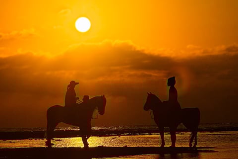 Two people riding horses on Gili Trawangan beach