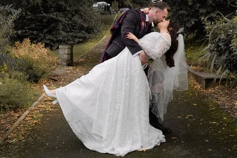 a bride and groom kissing on a path