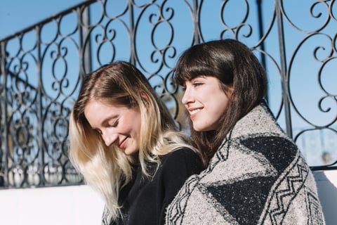 two women sitting on a bench in a park
