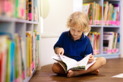 young boy in a library reading a book