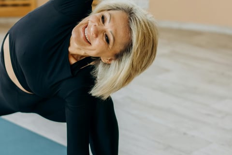 a woman in a black top and black pants stretching