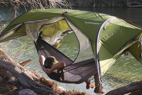 a person sitting in a hammock with a tent
