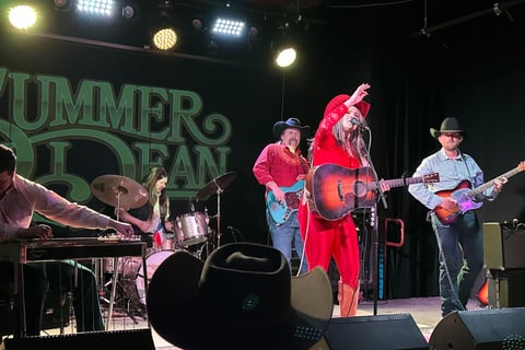 Country musician SUmmer Dean playing her acoustic guitar on stage
