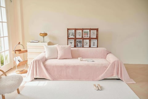 Cozy living: Soft pink reading sofa, matching pillows, and a peaceful nook by a large window.