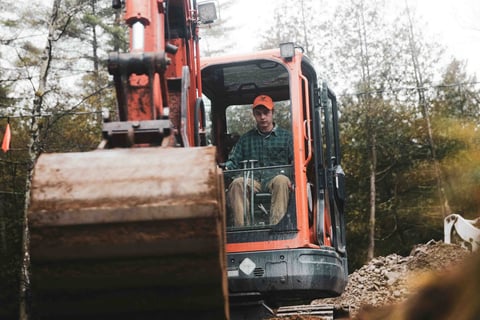 worker in an excavator digs a hole