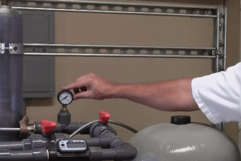 Man pointing to water pressure tank gauge
