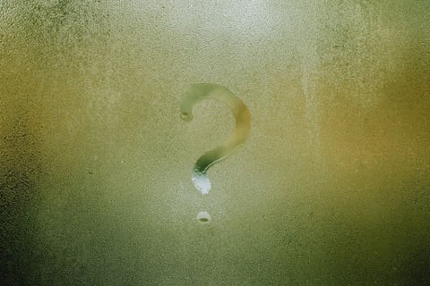 Question mark drawn on a rainy window questioning what is the deal with meditation.