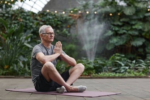 Elderly man meditating to clear his mind and rewire his mental health.