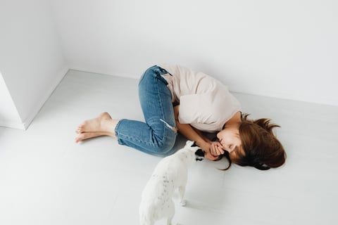 a woman sleeping on the floor while a dog stares at her (instantly relieving her mental health)