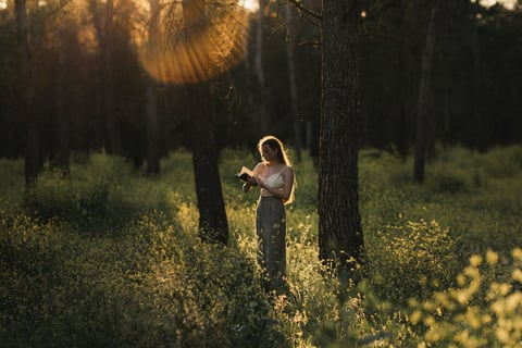a woman standing in the middle of the forest reading a book instantly enhancing her mental health.
