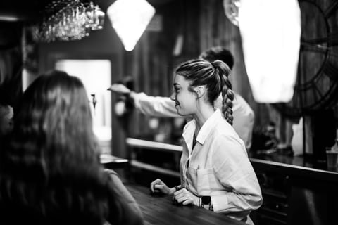 a woman is standing in a bar with a man