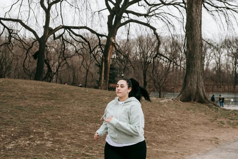 a woman in a gray hoodie running on a path