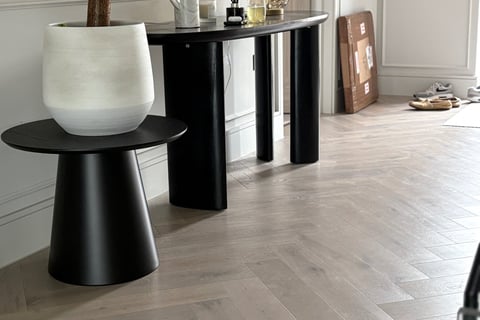 A light oak herringbone floor in a hallway with a step and small tbale