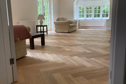 An oak herringbone floor in a living room with a red chair