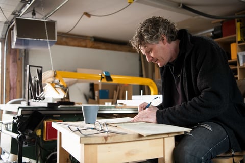 The artist in his studio. He is mid-fifties with unruly, wavy hair flecked with gray.