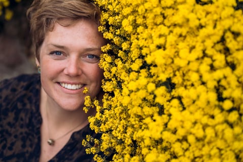 Billede af Gundas ansigt ved siden af et hav af gule blomster.