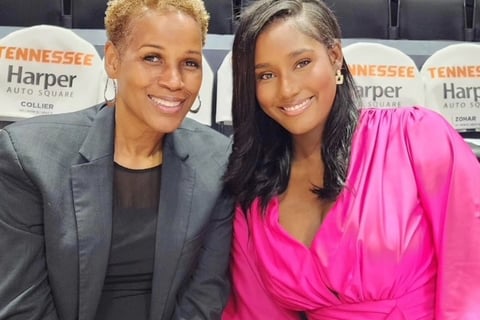 Two women sit together, enjoying a basketball game, surrounded by fans and the vibrant atmosphere.