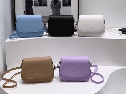 Una exhibición de cinco carteras hermosas en blanco, negro, celeste, morado y marrón