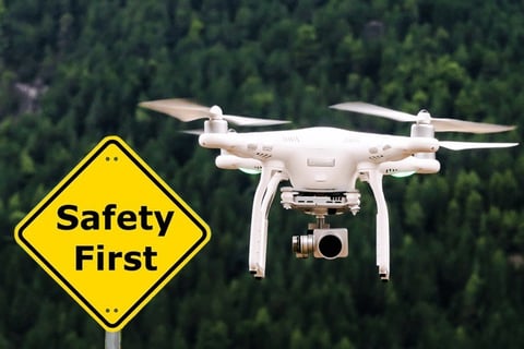 A white drone flying over a sign that says safety first.
