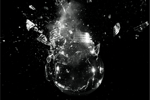 a glass bulb exploding against a dark background