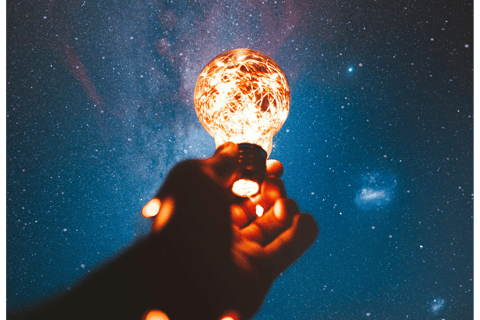 A lit bulb held up under a starry sky, symbol of the observing self