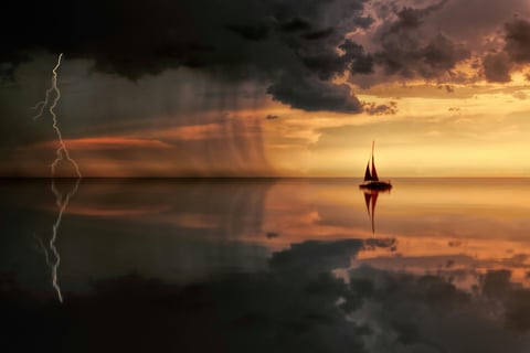 Image of a boat in the water, on one side the sky is stormy, on the other side it is clear