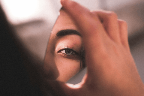 fragment of a woman's face reflected in a shard of broken mirror