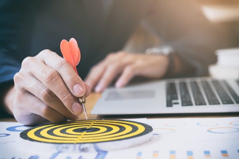 a person holding a dart and dart in front of a laptop