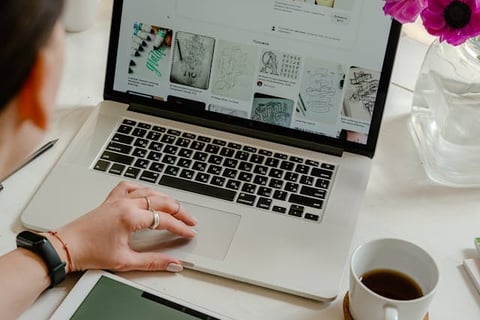Woman looking at laptop for hand-signed calligraphy designs for the logo she is creating on her iPad that say Creative