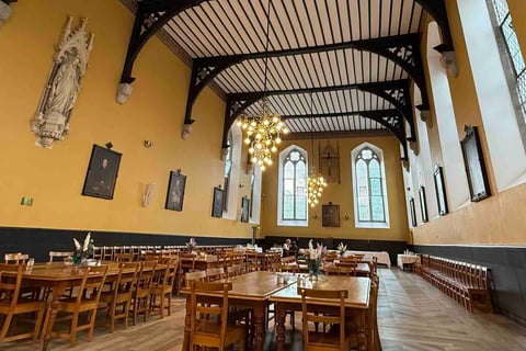 Pugin Hall with refectory tables separated by wide aisles and with parquet floor