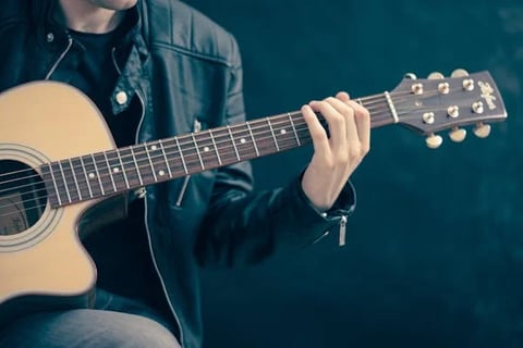 a man in a leather jacket playing guitar