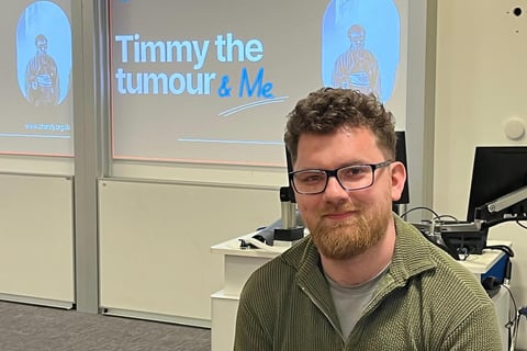 A photo of Chandy . In the background is a presentation with 'Timmy The Tumour & Me'.