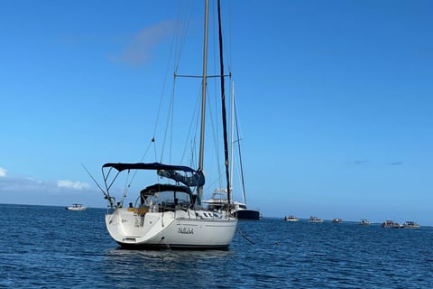 a sailboat in the water with a boat in the background