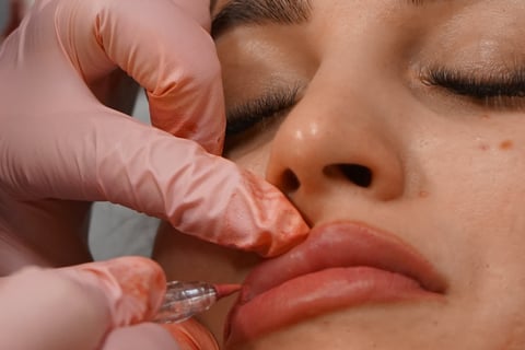 Eine Frau, die ihre Lippen von einer professionellen Kosmetikerin mit Permanent Make-up 