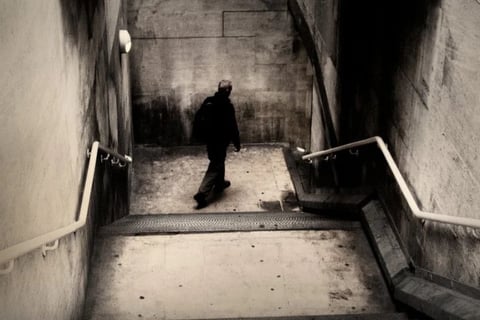 Lone figure walking down a concrete stairwell in a moody urban fine art photograph