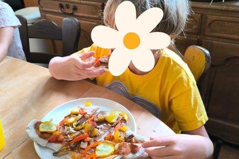 enfant mangeant un pizza cuisinée durant un stage nature et cuisine à Lustin