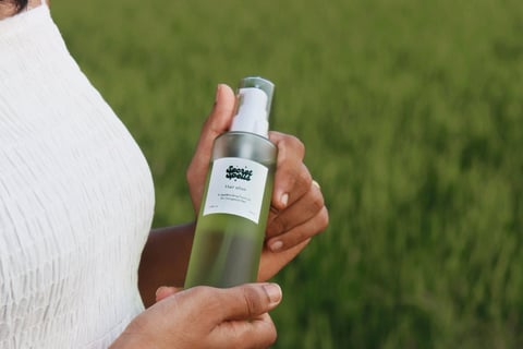 a woman in a white dress holding a bottle of green oil