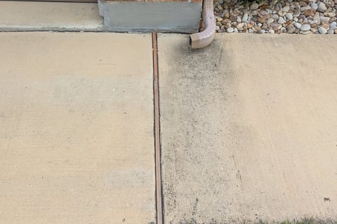 Before Picture of a sidewalk with a gutter downspout that stained the concrete.
