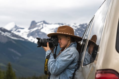 a woman in a hat taking a picture in Banff