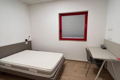 Una habitación con cama doble en el hotel de la escuela de vuelo para el alojamiento confortable de 