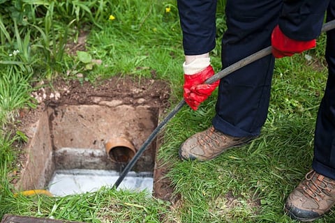 plumber cleaning out a sewer line with a long black hose