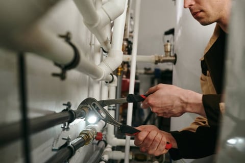 plumber using some channel locks to turn a pipe