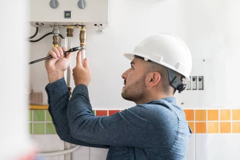 plumber tightening a pipe on a water heater