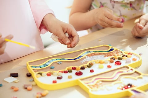 a child's hands are holding a beaded necklace