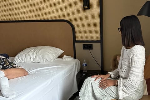Encadrante assise à côté d'une participante allongée sur un lit lors d'une session privée 