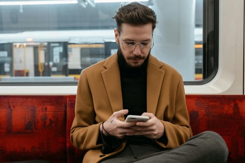 Man sitting on train holding phone