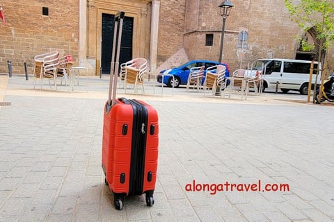 A small red carry-on standing in the middle of a square shows an ease of moving when packed light 