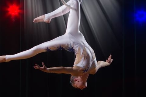 a woman in white and blue outfit performing a trick on a hoop
