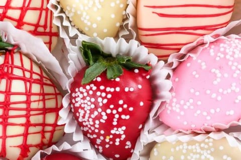 a box of chocolate covered strawberries with white and red sprinkles